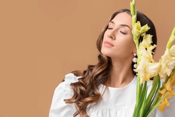 閉じた目と色の背景にグラジオラスの花の花束を持つ美しい女性 — ストック写真