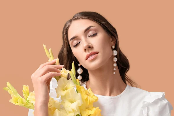 色の背景にグラジオラスの花の花束を保持して閉じ目を持つエレガントな女性 — ストック写真