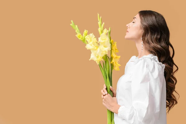 色の背景にグラジオラスの花の花束を保持しているファッショナブルな女性 — ストック写真