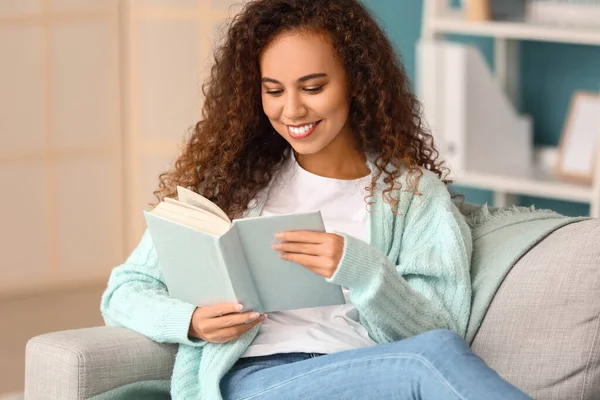 Young African American Woman Blue Cardigan Reading Book Sofa Home — Stock Photo, Image