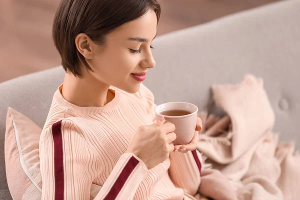 美しい若い女性飲むおいしいお茶でソファに家 — ストック写真