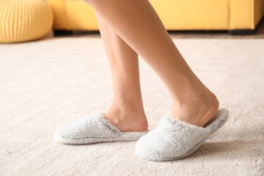 Evde rahat terlikleri olan genç bir kadın.