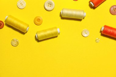 Sarı arkaplanda düğmeleri olan farklı dikiş iplikleri