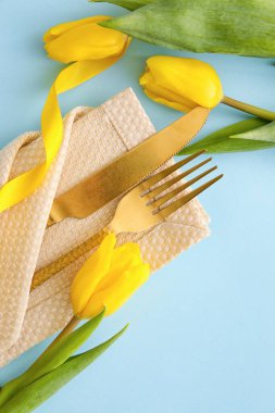Mavi arka planda lale çiçekleri olan şık çatal bıçak takımı