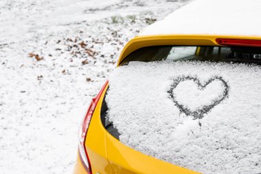 Kalp karla kaplı arabanın arka camına çizilmiş.