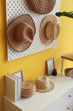 Sarı duvarda asılı şık şapkalı tahta.