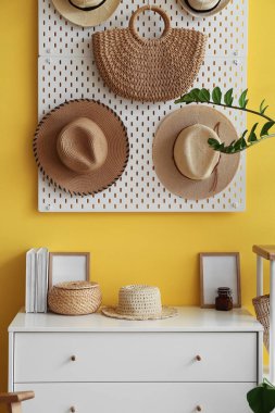 Çekmeceler, sapkalı tahta ve sarı duvarda asılı çanta.