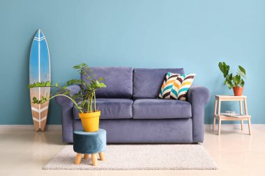 Mavi kanepesi, çiçekleri ve sörf tahtası olan şık bir oturma odası.