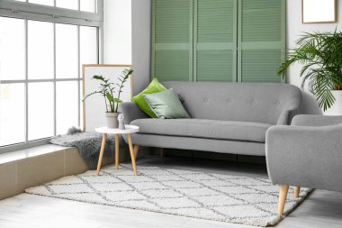 Oturma odasının içinde kanepe, sehpa ve çiçek var.