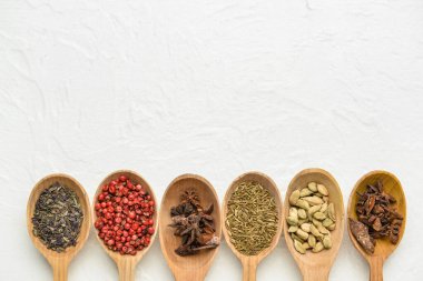 Hafif arka planda farklı baharatlı tahta kaşıklar, yakın plan.