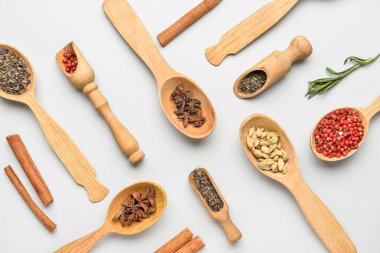 Ahşap kaşıklar ve kepçeler beyaz arka planda aromatik baharatlar