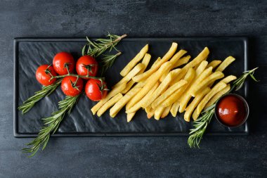 Lezzetli patates kızartması ve siyah arka planda taze domates.