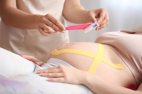 Fysiotherapeut Die Kinesio Tape Buik Van Een Zwangere Vrouw Aanbrengt — Stockfoto