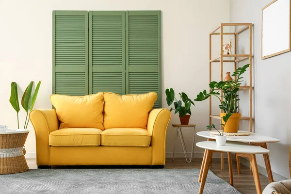 Interior of stylish living room with yellow sofa, coffee tables and houseplants