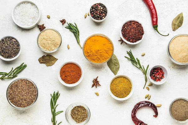 Composition with bowls of different spices on light background