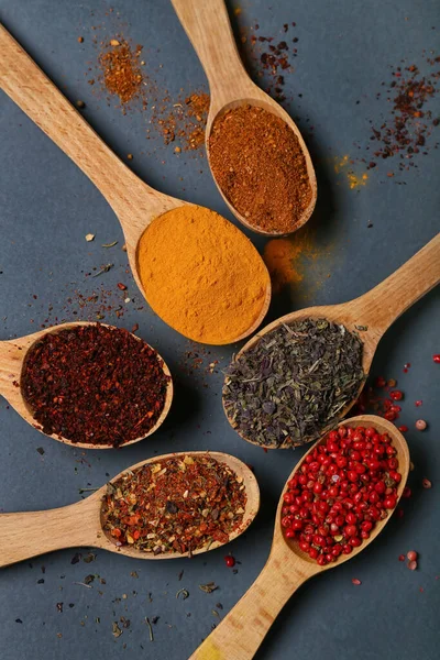 Koyu arka planda aromatik baharatlı tahta kaşıklar, yakın plan.