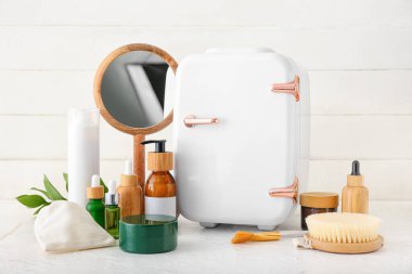 Işık masasında kozmetik ürünleri olan küçük bir buzdolabı.