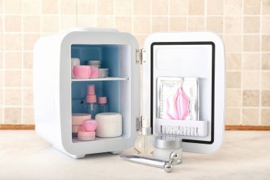 Masada kozmetik ürünleri olan küçük bir buzdolabı.