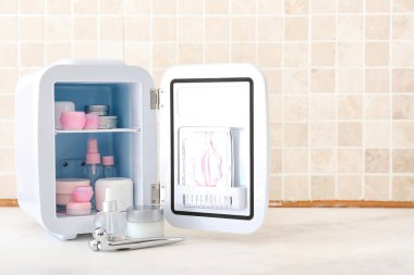 Masada kozmetik ürünleri olan küçük bir buzdolabı.