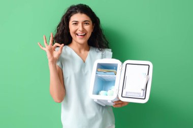 Gülümseyen kadın kozmetik buzdolabını açtı ve renk arka planında iyi bir hareket gösterdi