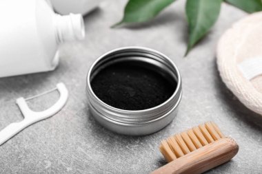 Kavanoz aktif kömür diş tozu ve diş fırçası ile gri arka planda, yakın plan.