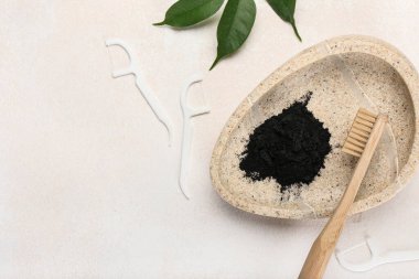 Fonda aktif kömür diş tozu ve diş fırçası olan bir kase.