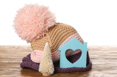 Beyaz arka planda, masa üzerinde şapka ve dekoratif köknar ağacı olan bir ev figürü. Isıtma kavramı