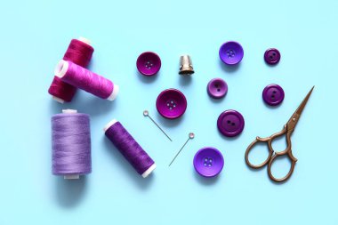 Mavi arkaplanda düğmeleri ve makasları olan iplik makaraları