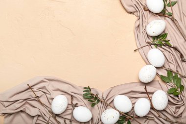 Renkli arkaplanda güzel Paskalya yumurtaları, ağaç dalları, yapraklar ve kumaşlar.