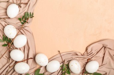 Renkli arkaplanda güzel Paskalya yumurtaları, ağaç dalları, yapraklar ve kumaşlar.