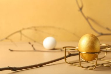 Altın Paskalya yumurtası ve ağaç dalına sahip tutucu, arka planda, yakın plan