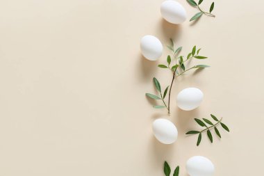 Paskalya yumurtaları ve bej arka planda yeşil dallar