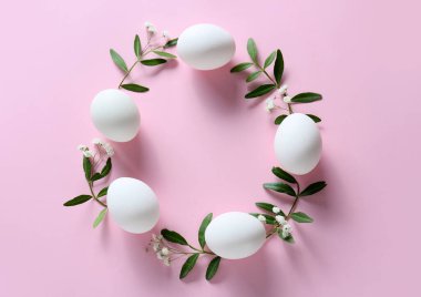 Paskalya yumurtaları ve pembe arka plandaki çiçeklerden yapılmış çerçeve