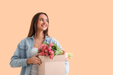 Laleli ve bej arka planda hediye kutusu olan mutlu genç bir kadın. Uluslararası Kadınlar Günü