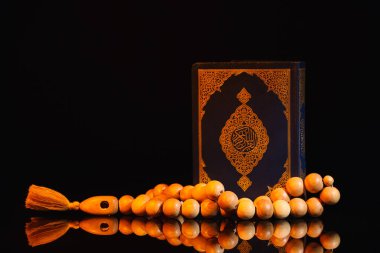 Koyu arkaplanda Kur 'an ve Müslüman dua boncukları