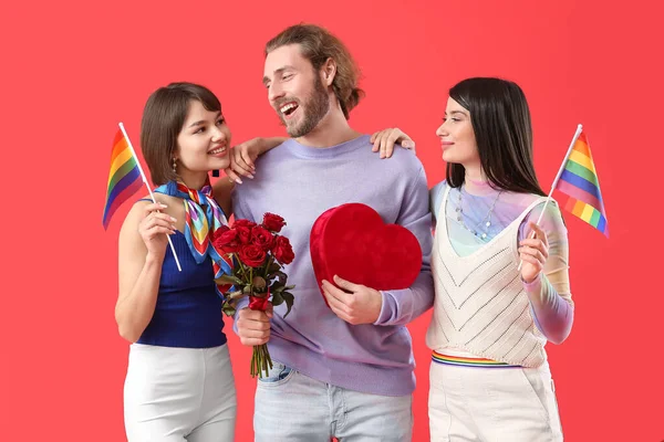 虹の旗 贈り物や色の背景に花を持つ男と2人の美しい女性 一夫多妻制とLgbtの概念 — ストック写真