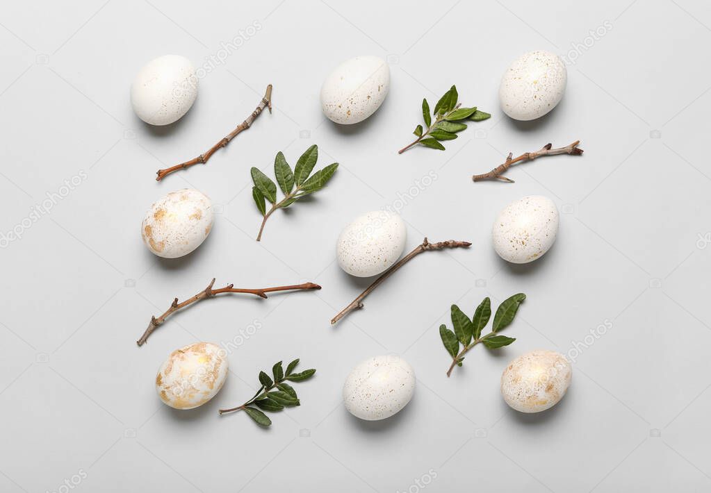 Composition with beautiful Easter eggs, tree branches and plant leaves on white background