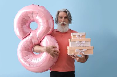 Duygusal son sınıf öğrencisi balonu şekil 8 şeklinde tutuyor ve renkli arka planda hediye kutuları yığıyor. Uluslararası Kadınlar Günü kutlamaları