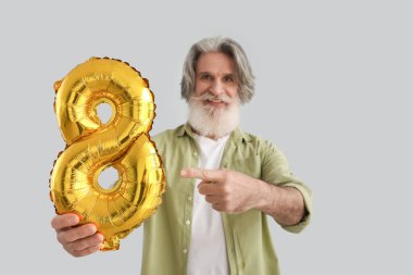 Üst düzey bir adam ışık arka planında şekil 8 şeklinde bir balonu işaret ediyor. Uluslararası Kadınlar Günü kutlamaları