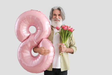 Şekil 8 şeklinde balon tutan son sınıf öğrencisi ve arka planda bir buket lale. Uluslararası Kadınlar Günü kutlamaları