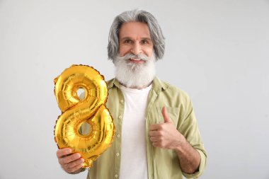 Balonlu yaşlı adam, balon şeklinde, arka planda baş parmağını gösteriyor. Uluslararası Kadınlar Günü kutlamaları