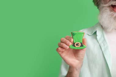 Yeşil arka planda kurabiyesi olan son sınıf öğrencisi, yakın plan. Aziz Patrick Günü kutlaması