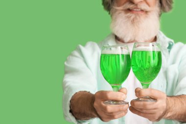 Yeşil arka planda bira bardakları olan son sınıf öğrencisi, yakın plan. Aziz Patrick Günü kutlaması