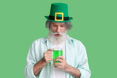 Yeşil arka planda bir bardak birası olan şapkalı son sınıf öğrencisi. Aziz Patrick Günü kutlaması