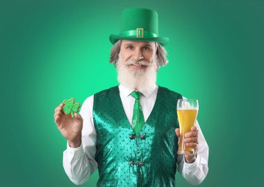 Yeşil arka planda kurabiyesi ve bir bardak birası olan son sınıf öğrencisi. Aziz Patrick Günü kutlaması