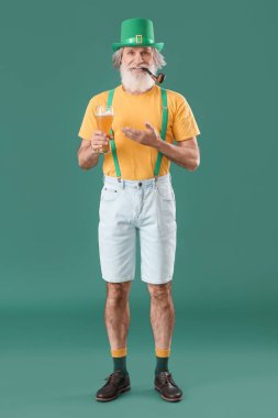 Yeşil arka planda sigara piposu ve bir bardak bira olan son sınıf öğrencisi. Aziz Patrick Günü kutlaması