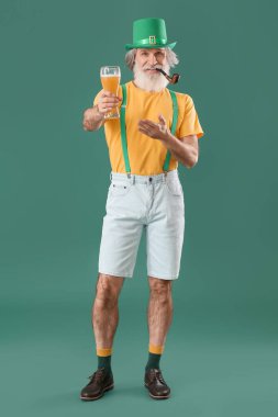 Yeşil arka planda sigara piposu ve bir bardak bira olan son sınıf öğrencisi. Aziz Patrick Günü kutlaması