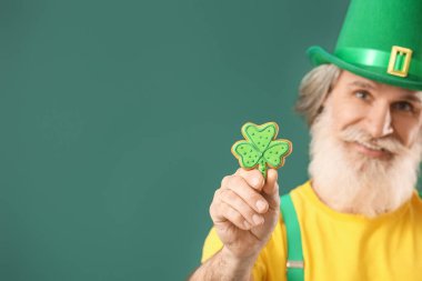 Yeşil arka planda kurabiyesi olan son sınıf öğrencisi, yakın plan. Aziz Patrick Günü kutlaması