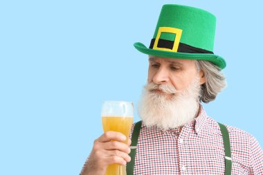 Mavi arka planda bir bardak birası olan son sınıf öğrencisi, yakın plan. Aziz Patrick Günü kutlaması