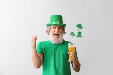 Hafif arka planda bir bardak birayla şapkalı son sınıf öğrencisi. Aziz Patrick Günü kutlaması